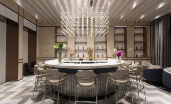 An elegant dining area is located in front of the bar, featuring tables and chairs at Golden Tulip Shanghai