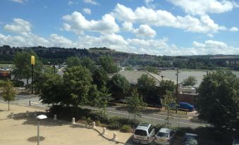 a view from a window , looking out at a city with trees and buildings , under a blue sky with white clouds at Premier Inn Rochester