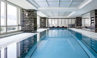 There is an indoor pool with large windows that overlook the water and a tiled floor in front at The Langham, Shenzhen