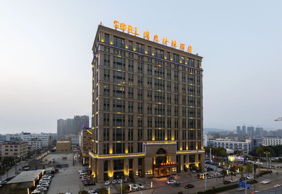 The illuminated hotel stands in front of a cityscape, surrounded by other buildings at Sorl Bund Hotel Ruian