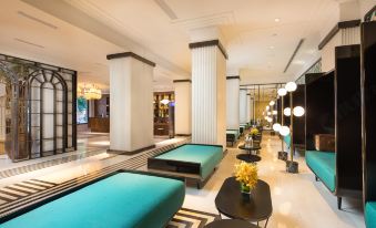 The lobby features a spacious seating area with a large table, chairs, and other furniture at Jinjiang Metropolo Shanghai Xintiandi Hotel
