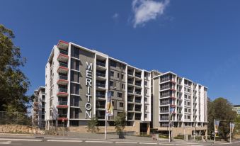 "a modern apartment building with the name "" menton "" on it , situated near a street and under a blue sky" at Meriton Suites North Ryde