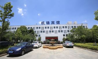"a large white building with the word "" shanghai ai laboratory "" written on it , surrounded by cars parked in front of it" at Airport Hotel