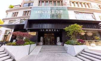 The front entrance of a hotel is adorned with an oriental sign, while other buildings surround it at Ji Hotel (Shanghai Jing'an Temple Kangding Road)