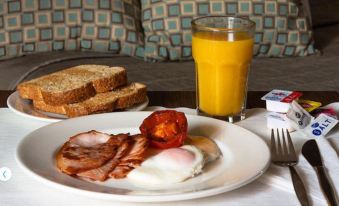 a plate of breakfast food , including eggs and bacon , is on a table next to a glass of orange juice at Bankstown Motel 10