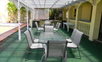 a patio with a large glass table surrounded by chairs , and a pergola over the area at Tropic Coast Motel