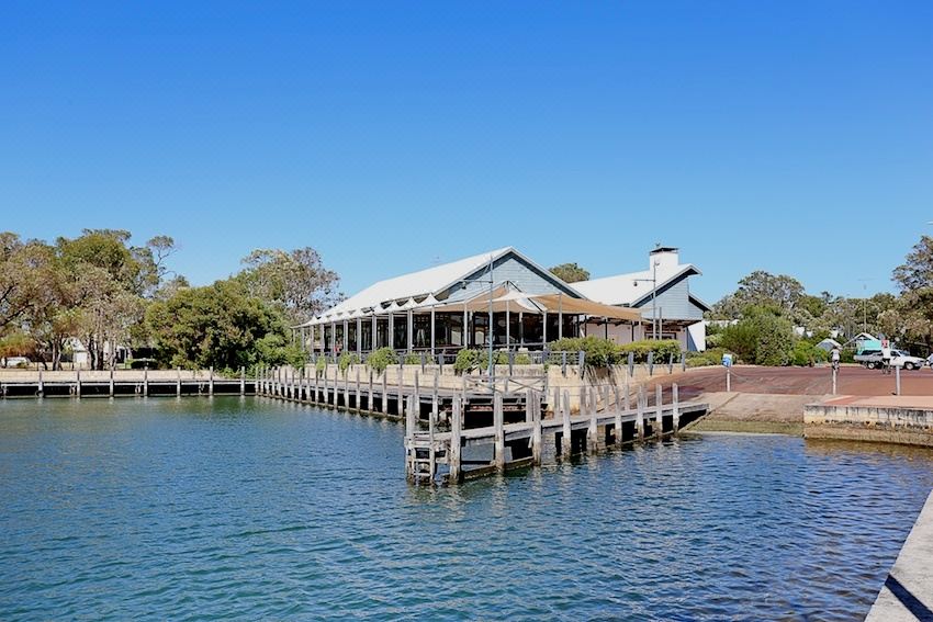 a wooden dock extending into a body of water , with a building on one side and a pier on the other at Mandurah Quay Resort