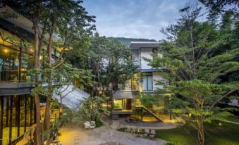 a modern house surrounded by lush greenery and trees , with a paved courtyard in the middle at Villa Moreeda
