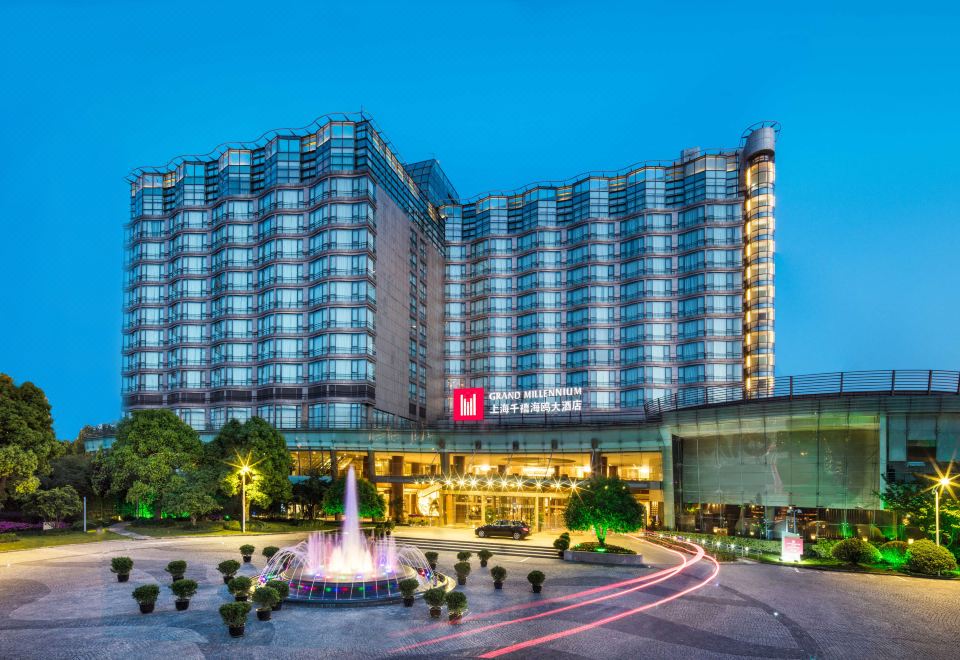 On an overcast day, the hotel building stands in front, contrasting with the blue sky at Grand Millennium Shanghai HongQiao
