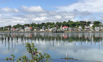 a picturesque view of a small town surrounded by water , with a dock extending into the river at Friars Bay Inn & Cottages