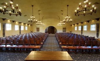 a large , empty conference room with wooden chairs and tables , chandeliers hanging from the ceiling , and a long row of windows on the at Tubac Golf Resort & Spa