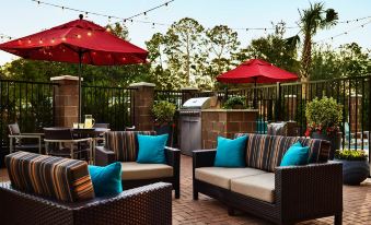 a patio area with several couches and chairs arranged around a grill , creating a comfortable outdoor seating area at TownePlace Suites Grand Rapids Airport