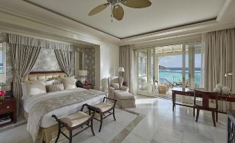 a luxurious bedroom with a large bed , two chairs , and a balcony overlooking the ocean at Mandarin Oriental, Canouan