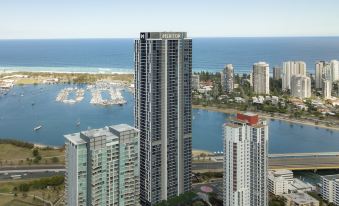 a high - rise building overlooking a body of water , with boats in the distance and a few buildings visible at Meriton Suites Southport
