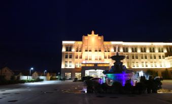 a large , illuminated building with a fountain in front of it at night , surrounded by cars at Spring Hotel
