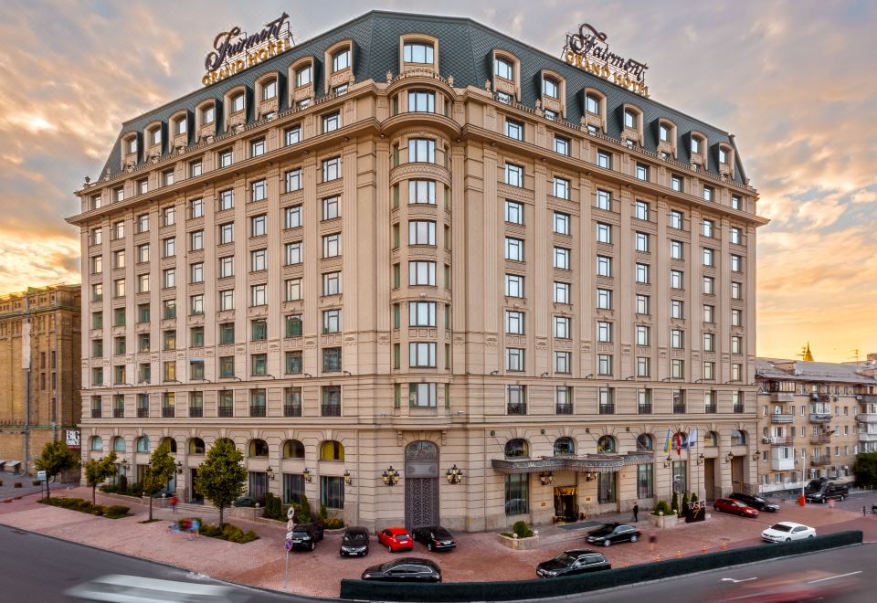 "a large , ornate hotel building with the name "" tychy "" on its top , surrounded by cars and other buildings" at Fairmont Grand Hotel - Kyiv