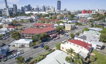 an aerial view of a city with buildings , roads , and palm trees , under a clear blue sky at Brisbane Backpackers Resort