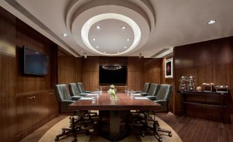 There is a large conference room with a wooden table and chairs in the center, as well as an adjacent office at Cordis, Hong Kong
