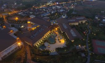 an aerial view of a large hotel complex with multiple buildings , a swimming pool , and surrounding greenery at The Singhasari Resort Batu