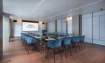 A conference room is equipped with tables, chairs, and a projector screen mounted on the front at Campanile Hotel (Shanghai Jing'an)