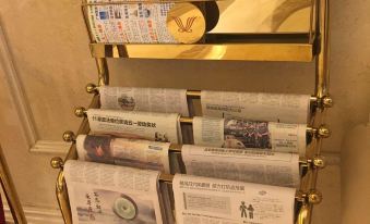 There is a rack in the middle room next to an ironing board that holds books and magazines at Vienna Hotel (Guangzhou railway station & Xiaobei subway station)