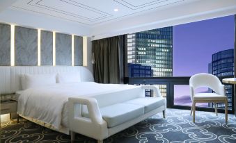 a modern bedroom with white walls , a large bed , and a chair near a window at Central Hotel