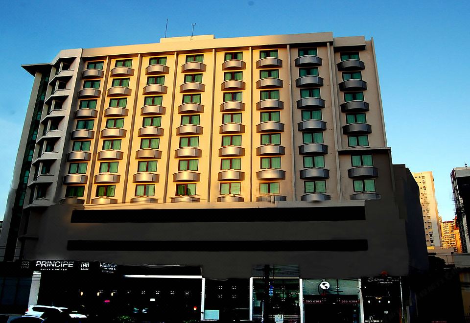a large building with multiple floors and windows , standing under a clear blue sky , and traffic lights visible at the bottom of the image at Hotel Principe
