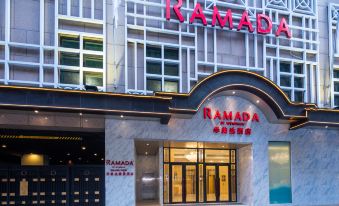 The front entrance of a hotel is depicted, featuring a sign above it and an illuminated doorway at Ramada Hong Kong Grand View