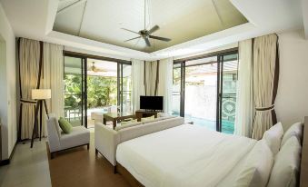 a spacious bedroom with a large bed , a television , and a window overlooking a pool at Robinson Khao Lak