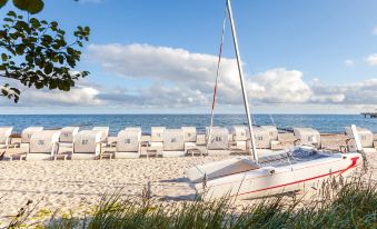 a sandy beach with several sailboats docked on the shore , creating a picturesque scene for visitors at Grand Hotel Heiligendamm - the Leading Hotels of the World