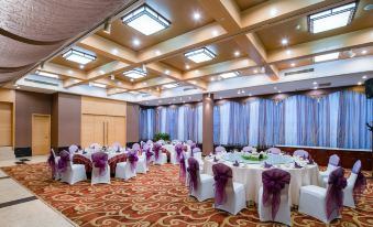 a large banquet hall with multiple tables covered in white tablecloths and chairs arranged for a formal event at Paradise Hotel