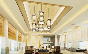a large , well - lit lobby with high ceilings and multiple chandeliers , creating a luxurious and modern atmosphere at Sanya Xizang Hotel