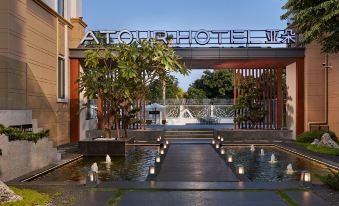 The hotel has a front entrance adorned with water features and plants at Atour Hotel