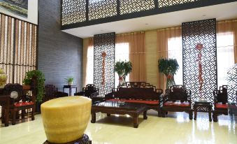 a spacious living room with a large couch , a wooden coffee table , and several chairs arranged around it at Spring Hotel