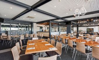 a modern , well - lit restaurant with wooden tables and chairs arranged in a dining area setting at Berri Hotel