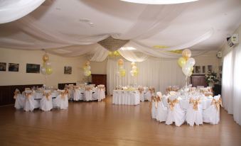 a large banquet hall with multiple tables and chairs , balloons hanging from the ceiling , and a doorway leading to another room at Picton Valley Motel Australia