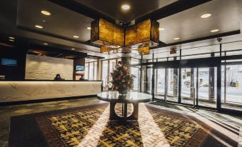 a large hotel lobby with a reception desk and a dining area , surrounded by comfortable seating at The Explorer Hotel