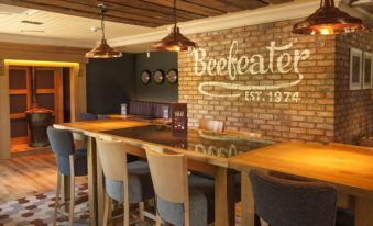 "a bar area with wooden tables and chairs , along with a brick wall that says "" beefeater .""." at Premier Inn Bagshot