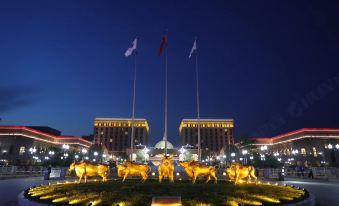 In front of a statue, there is an ornate building in a city at night at Guoce International Conference and Exhibition Center
