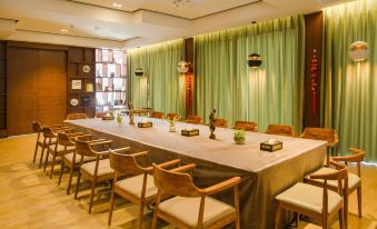 a long table with chairs and wine bottles is set up in a room with green curtains at Gengting Hotel