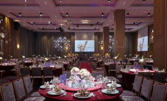 A ballroom is arranged for an event, featuring white draped tables and chairs at Caesar Metro Taipei