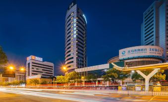 A cityscape at night featuring a building in the foreground and another building situated behind it at Atour Hotel (Yiwu International Trade City)