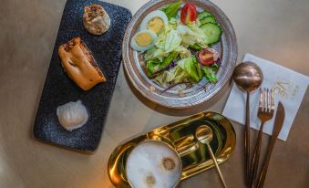 A table is set with dishes and bowls, including an egg and a salad in the center at Yuzhan No.8 Art Hotel (Shanghai Beach Branch)