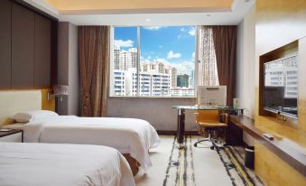 a hotel room with two beds , a desk , and a view of a city skyline through the window at Silver Sea Hotel