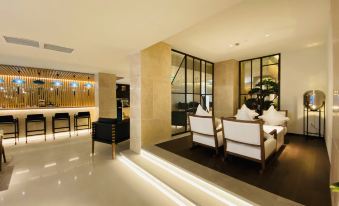 a spacious living area with contemporary furniture and tables at Ginco Hotel