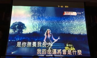 a television screen displays a woman singing on stage with chinese text in the background at Gengting Hotel