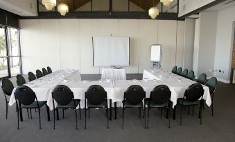 a large conference room set up for a meeting , with tables and chairs arranged in a semicircle at Mandurah Quay Resort