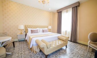 a luxurious bedroom with a large bed , white linens , and gold accents , situated in a room with yellow walls and a chandelier at Rizal Park Hotel