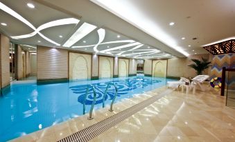 an indoor swimming pool surrounded by a lounge area , with several chairs placed around the pool at Central Hotel