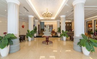 a large , well - lit hotel lobby with high ceilings , white columns , and multiple potted plants at Paradise Hotel